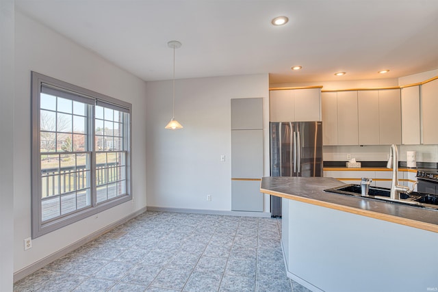 kitchen featuring stainless steel fridge, sink, and hanging light fixtures