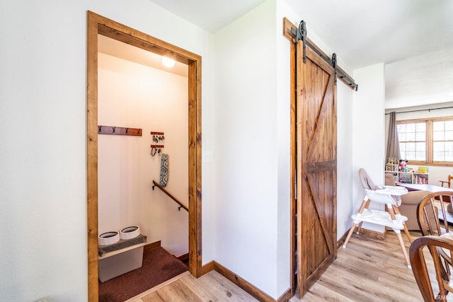 hallway featuring a barn door and light hardwood / wood-style floors