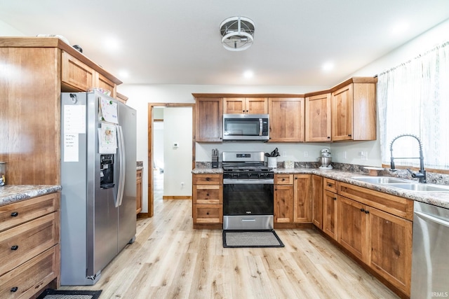 kitchen featuring light hardwood / wood-style flooring, appliances with stainless steel finishes, sink, and light stone counters