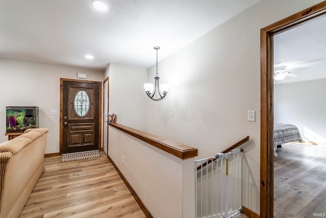 foyer with light hardwood / wood-style flooring and ceiling fan with notable chandelier