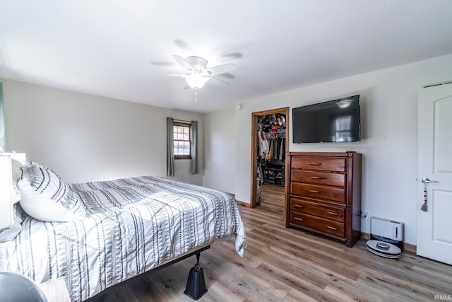 bedroom with a spacious closet, light hardwood / wood-style flooring, a closet, and ceiling fan