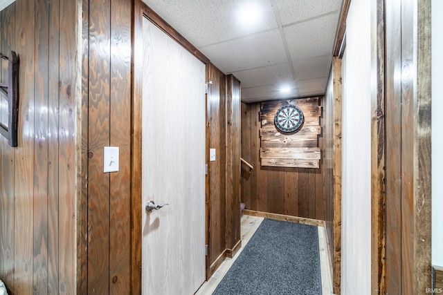 hallway with wooden walls and a paneled ceiling