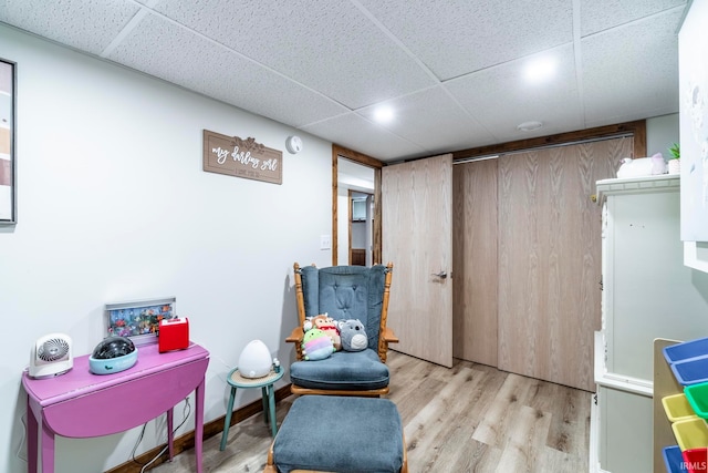 living area featuring a drop ceiling and light wood-type flooring