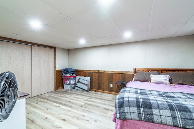 bedroom featuring light hardwood / wood-style floors, a closet, and wood walls