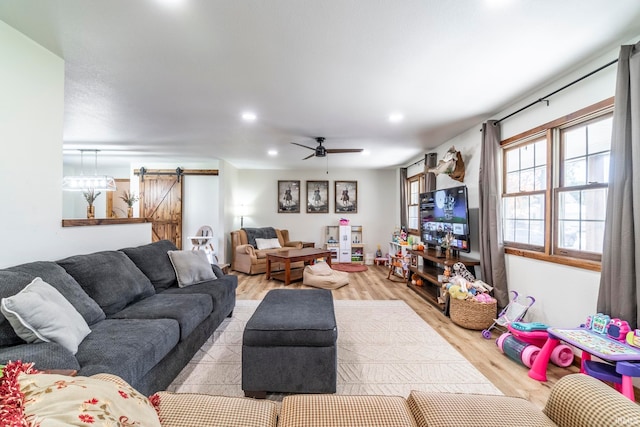 living room featuring ceiling fan, light hardwood / wood-style flooring, and a barn door