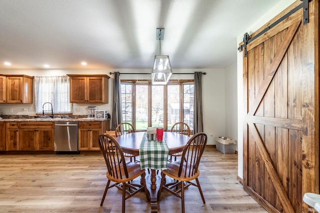 dining room featuring light hardwood / wood-style floors, a barn door, and plenty of natural light