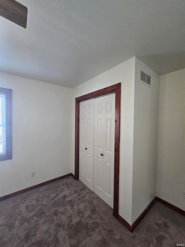 unfurnished bedroom featuring a closet and dark colored carpet