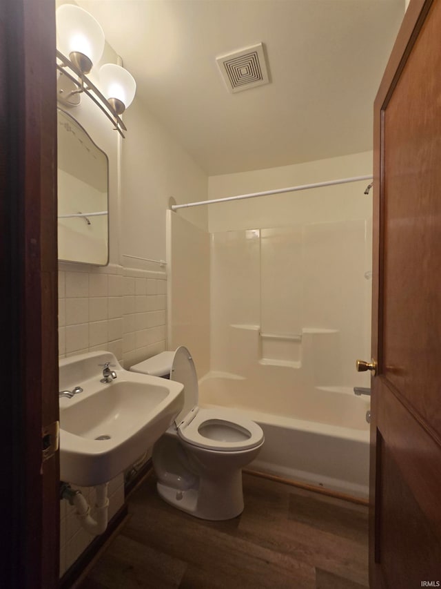 full bathroom featuring tasteful backsplash, wood-type flooring, toilet, sink, and shower / bath combination