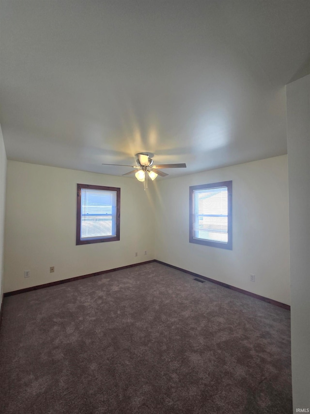 unfurnished room with dark carpet and ceiling fan