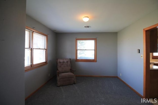 living area featuring dark carpet and plenty of natural light