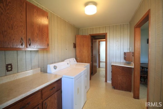 laundry area featuring independent washer and dryer, wood walls, and cabinets