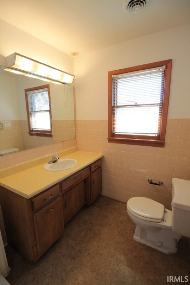 bathroom with vanity, toilet, tile walls, and plenty of natural light