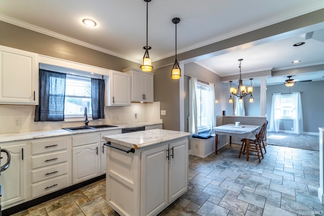 kitchen with decorative backsplash, white cabinets, sink, decorative light fixtures, and a center island