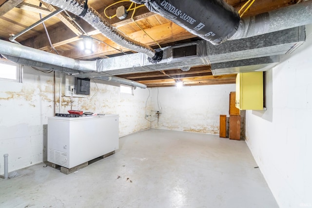 basement featuring electric panel and refrigerator