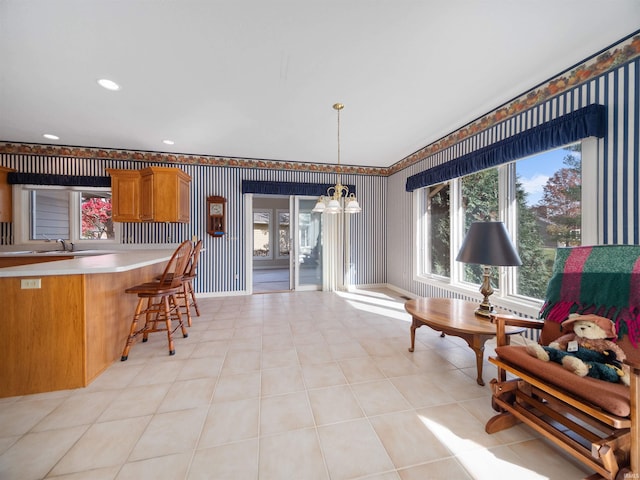 kitchen with sink, a kitchen bar, pendant lighting, light tile patterned floors, and an inviting chandelier