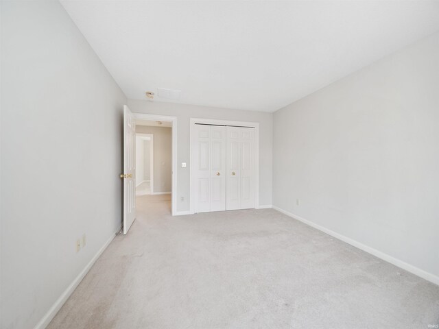 unfurnished bedroom with light carpet and a closet