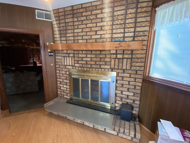 interior details featuring wooden walls, a fireplace, visible vents, and wood finished floors