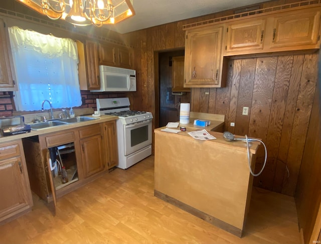 kitchen featuring white appliances, a sink, light countertops, pendant lighting, and a notable chandelier