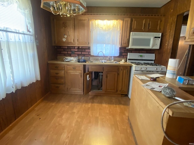 kitchen featuring brown cabinets, light countertops, light wood-style floors, a sink, and white appliances