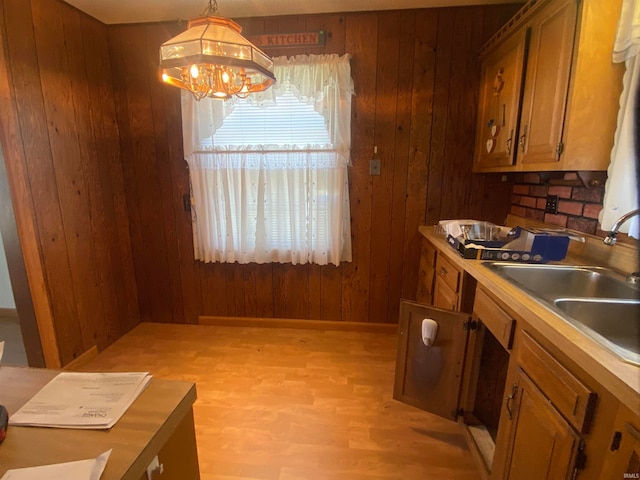 kitchen featuring hanging light fixtures, brown cabinetry, light countertops, and a sink