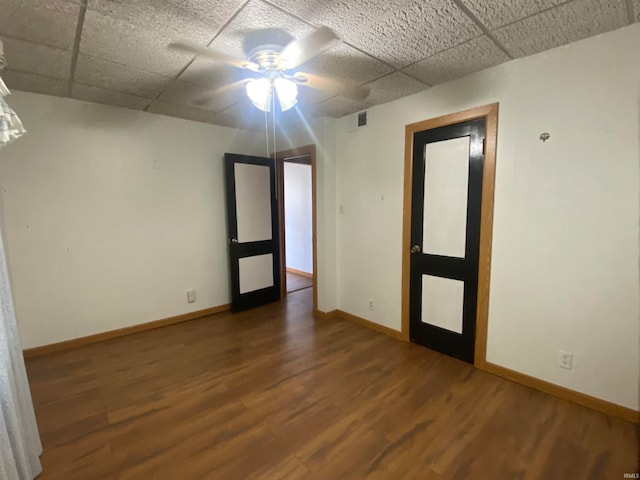 spare room with a paneled ceiling, wood finished floors, visible vents, and baseboards