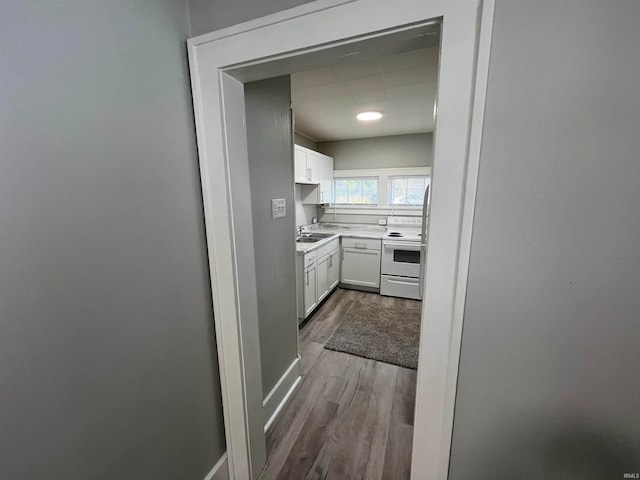 kitchen with white cabinetry, white electric range, hardwood / wood-style flooring, and sink