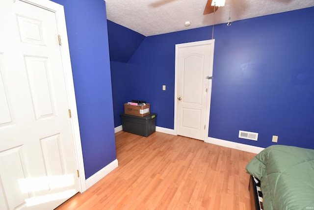 interior space with light hardwood / wood-style floors, a textured ceiling, vaulted ceiling, and ceiling fan