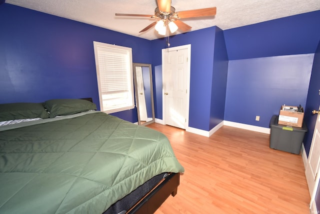 bedroom featuring ceiling fan, wood-type flooring, and a textured ceiling