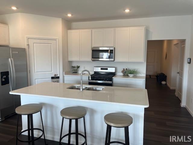 kitchen with sink, appliances with stainless steel finishes, a kitchen island with sink, and white cabinets