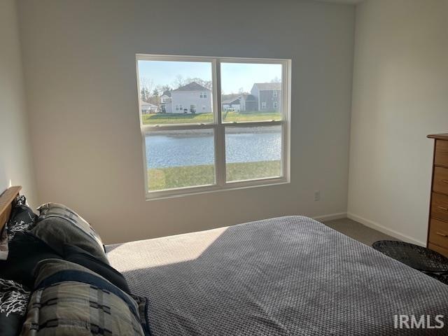 bedroom featuring a water view and carpet