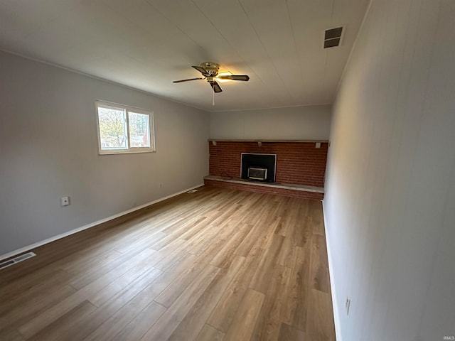 unfurnished living room with light hardwood / wood-style floors, a brick fireplace, and ceiling fan