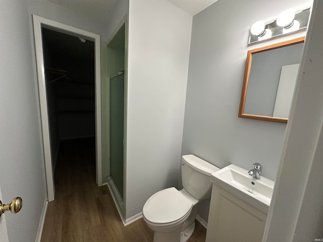 bathroom with toilet, hardwood / wood-style flooring, vanity, and a shower with door