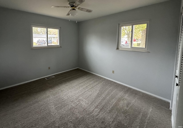 carpeted spare room featuring a healthy amount of sunlight and ceiling fan