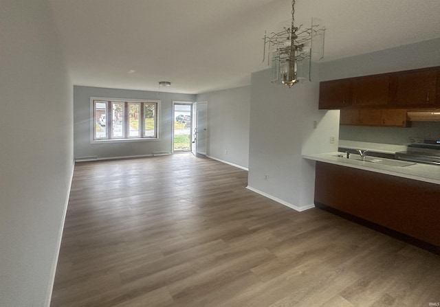 interior space with a chandelier, light wood-type flooring, sink, ventilation hood, and electric range oven