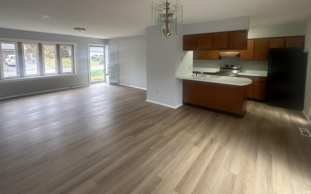 kitchen with black refrigerator, hanging light fixtures, stainless steel electric stove, light hardwood / wood-style flooring, and sink