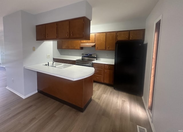 kitchen with black refrigerator, stainless steel electric range, light hardwood / wood-style flooring, and kitchen peninsula