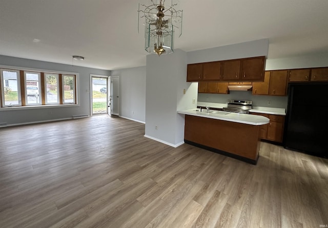 kitchen featuring stainless steel electric stove, kitchen peninsula, light wood-type flooring, black refrigerator, and sink