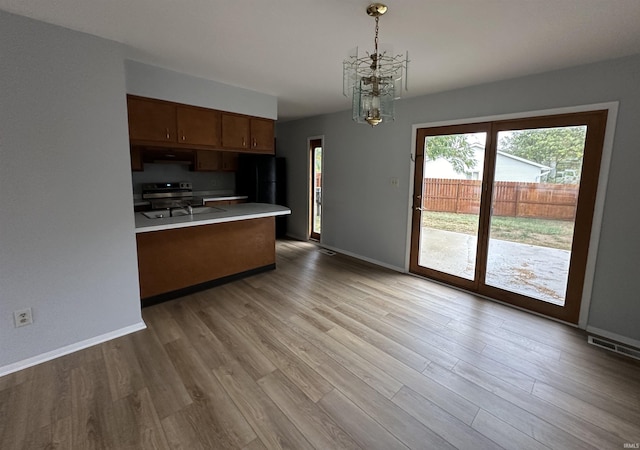 kitchen with a chandelier, electric range, light hardwood / wood-style flooring, and decorative light fixtures