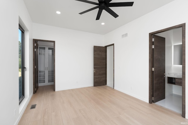 unfurnished bedroom with light hardwood / wood-style floors, access to outside, ensuite bathroom, and ceiling fan