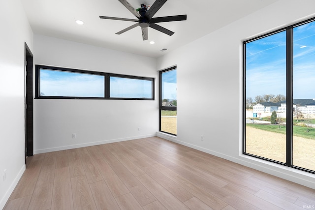 empty room with light wood-type flooring, a healthy amount of sunlight, and ceiling fan