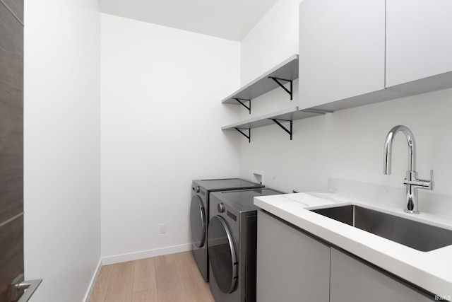 washroom with sink, light hardwood / wood-style floors, cabinets, and washer and clothes dryer