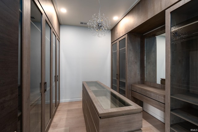 walk in closet with an inviting chandelier and light wood-type flooring