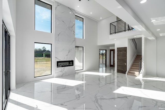 living room featuring a high end fireplace, a towering ceiling, and plenty of natural light