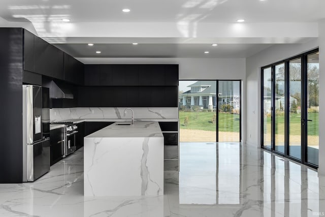 kitchen with appliances with stainless steel finishes, a healthy amount of sunlight, sink, and an island with sink