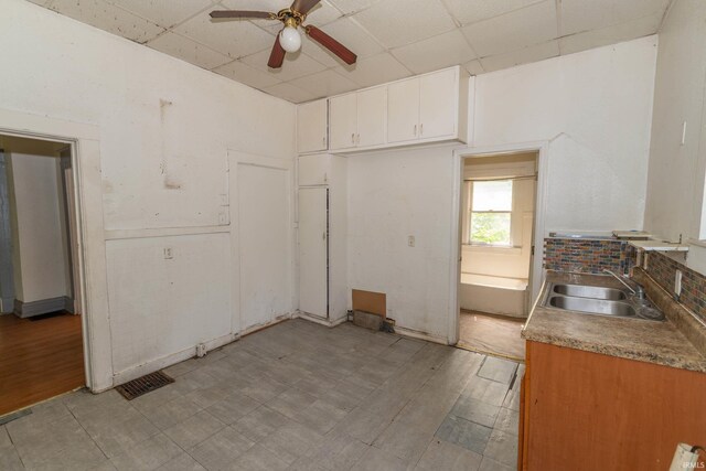 1815 Elwood Ave, South Bend, IN 46628 - kitchen featuring a sink, ceiling fan, a paneled ceiling, white cabinetry, and light floors