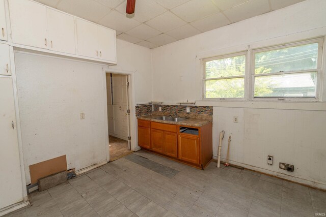 1815 Elwood Ave, South Bend, IN 46628 - kitchen featuring a drop ceiling, light flooring, brown cabinetry, a sink, and white cabinets