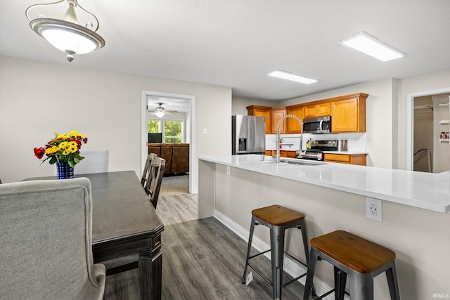 kitchen with stainless steel appliances, a breakfast bar, kitchen peninsula, and dark hardwood / wood-style floors