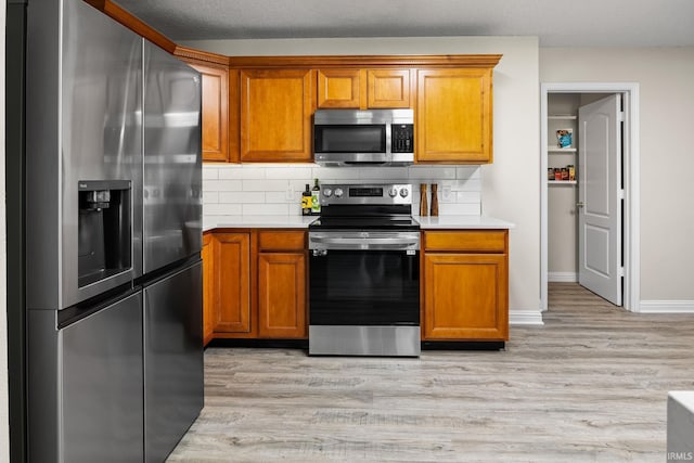 kitchen with appliances with stainless steel finishes, light hardwood / wood-style flooring, and decorative backsplash