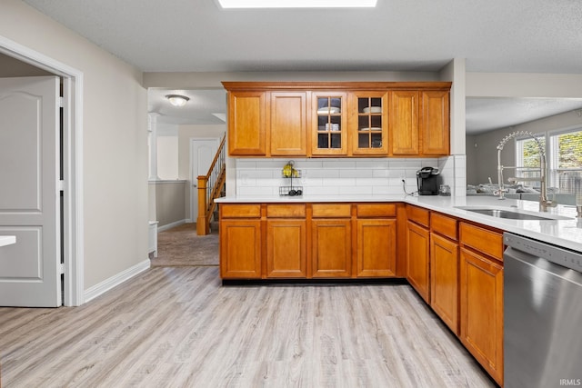 kitchen featuring tasteful backsplash, sink, dishwasher, light wood-type flooring, and a textured ceiling