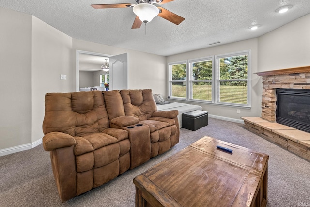 living room with carpet, a stone fireplace, a textured ceiling, and ceiling fan